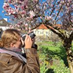 Junge Frau fotografiert mit ihrer Kamera eine Magnolie ©Bienhaus